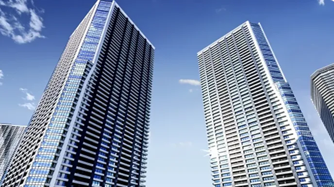 青空の下にそびえる高層マンションの外観。不動産の貸し出し検討時の査定価格をイメージさせる建物写真。