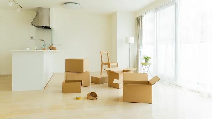 転勤で自宅を貸す準備をイメージさせる、段ボール箱が置かれた明るいリビングの写真。