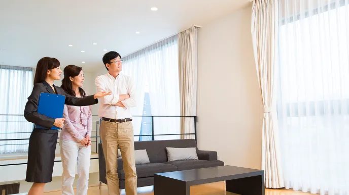 室内を案内するスタッフと、説明を聞きながら部屋を見学する二人が立っている様子の写真。